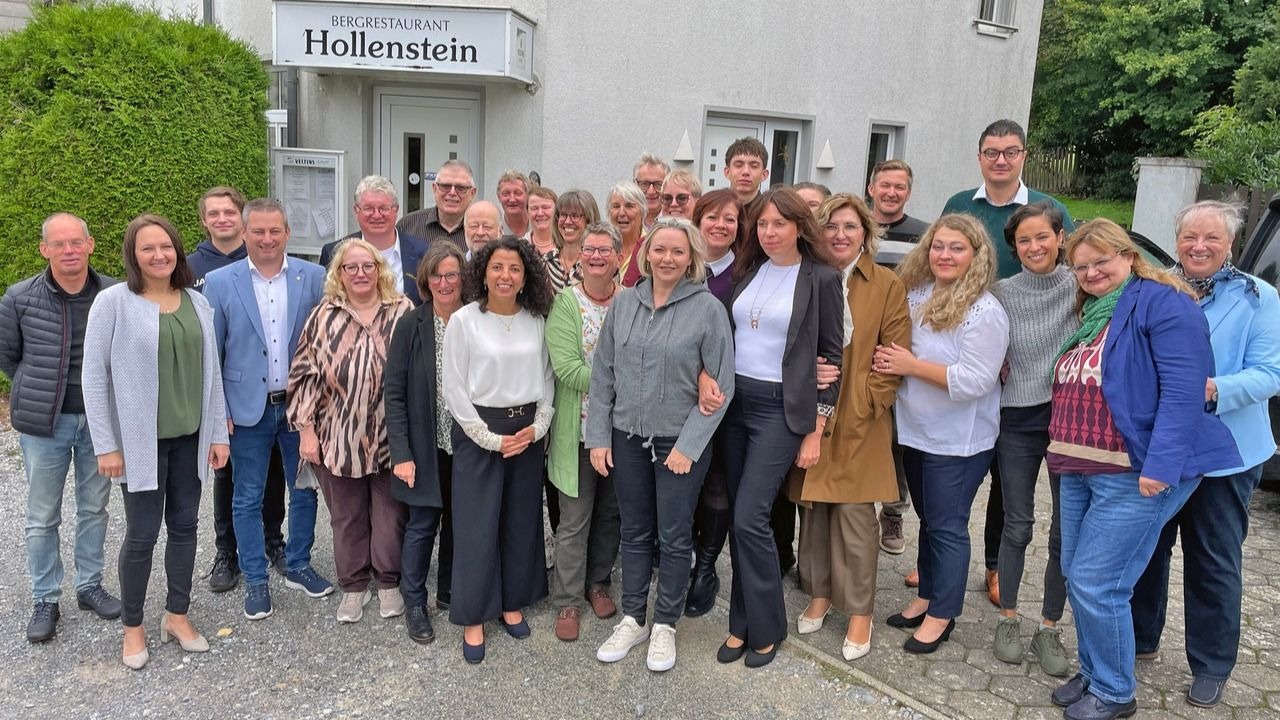 Etwa 25 Frauen und Männer stehen lächelnd vor dem Bergrestaurant Hollenstein
