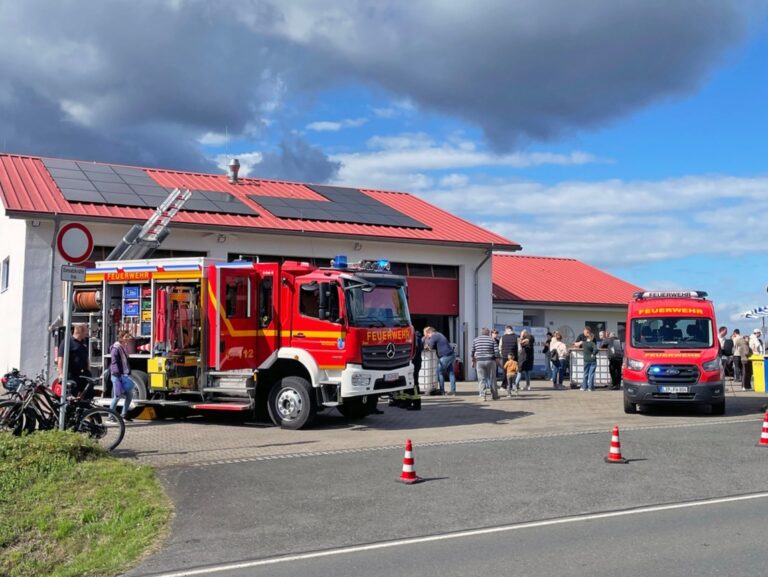 Zwei rote Feuerwehrautos vor einem Feuerwehrhaus mit Besuchern beim Tag der offenen Tür