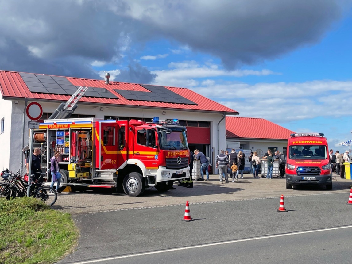 Zwei rote Feuerwehrautos vor einem Feuerwehrhaus mit Besuchern beim Tag der offenen Tür