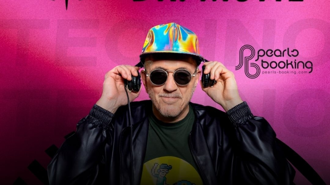 Dr. Motte mit Sonnenbrille und bunter Kappe hält Kopfhörer an die Ohren und lächelt leicht