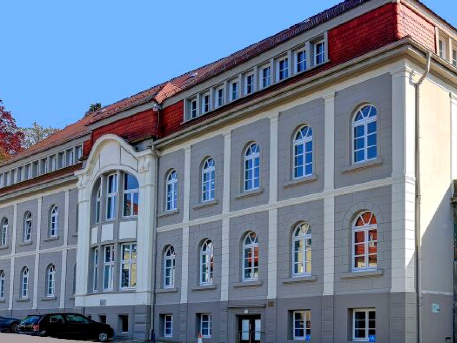 Großes graues Gebäude des Gesundheitszentrums Oerlinghausen mit rotem Mansarddach und vielen Bogenfenstern