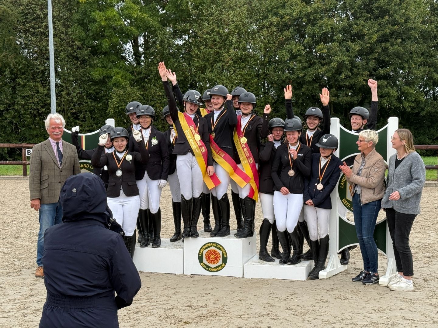 Reiterinnen als Lippische Dressur Meister Mannschaft 2026 auf einem Siegerpodest, mit Medaillen und Bändern, jubelnd