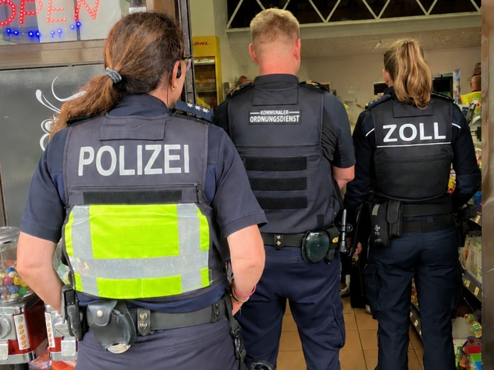 Drei Beamte von Polizei, Kommunalem Ordnungsdienst und Zoll betreten einen Kiosk