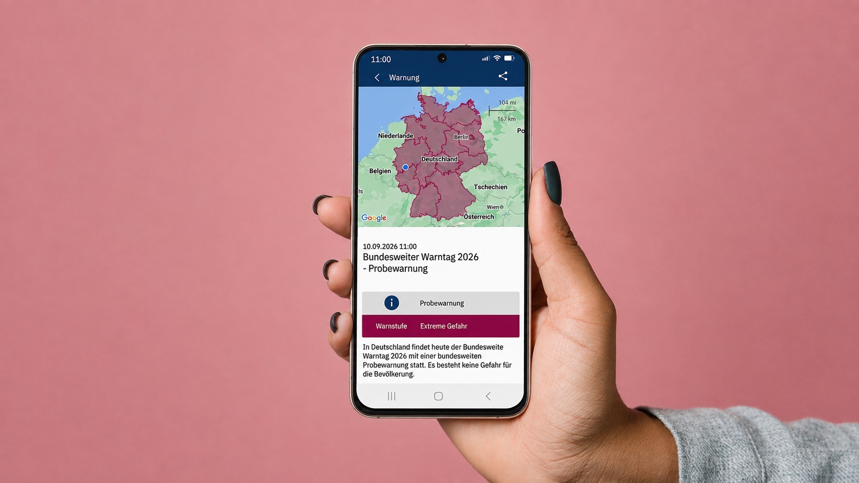 Eine Hand hält ein Smartphone, das eine Warn-App mit Deutschlandkarte und Informationen zum Bundesweiten Warntag 2026