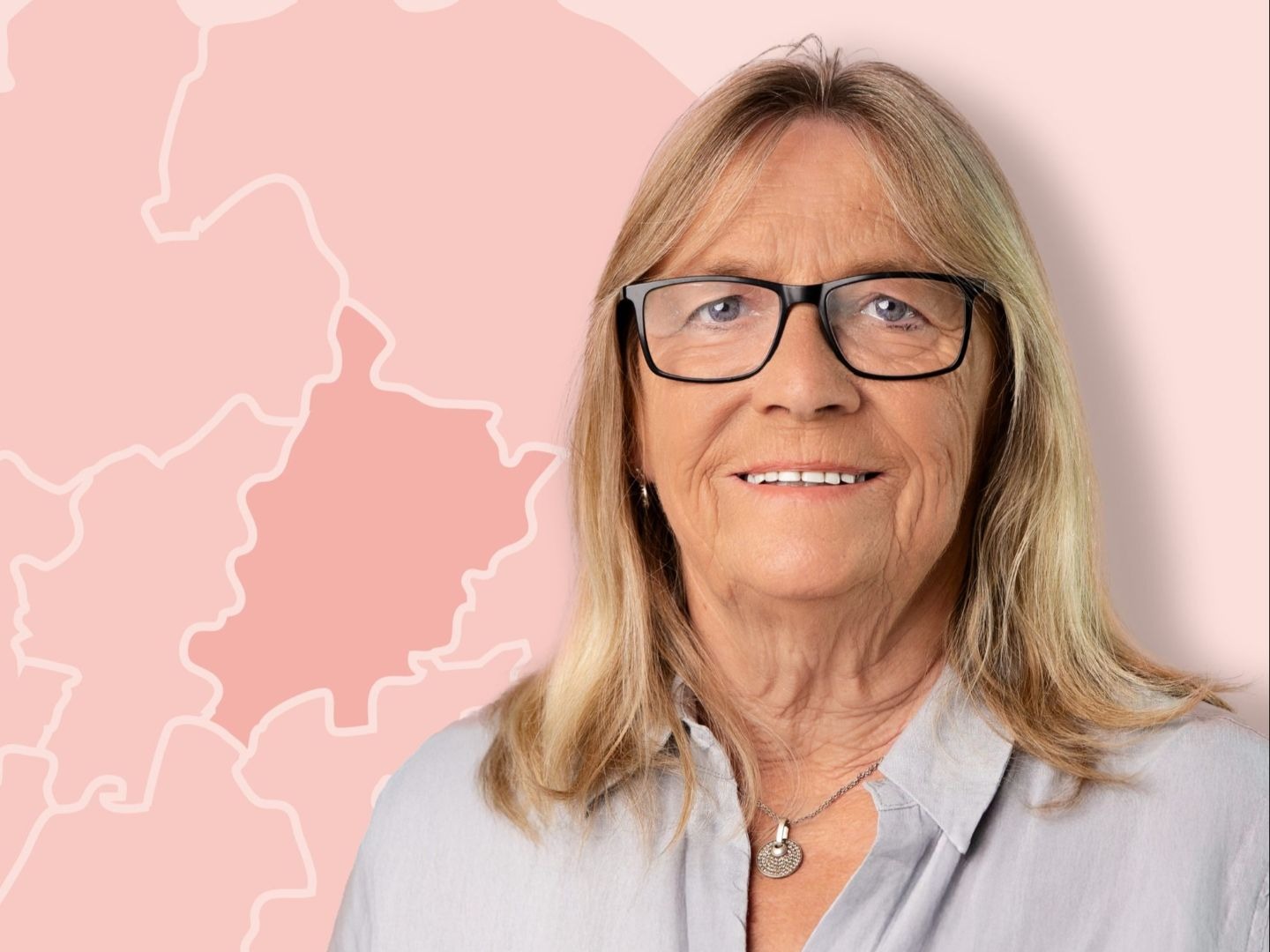 Regina Suett lächelt und trägt Brille vor pinkem Hintergrund mit Landkartenumrissen