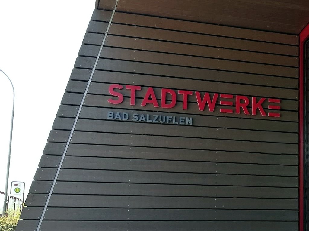 Roter Schriftzug STADTWERKE und darunter BAD SALZUFLEN in Grau auf einer Fassade aus horizontalen Holzlatten