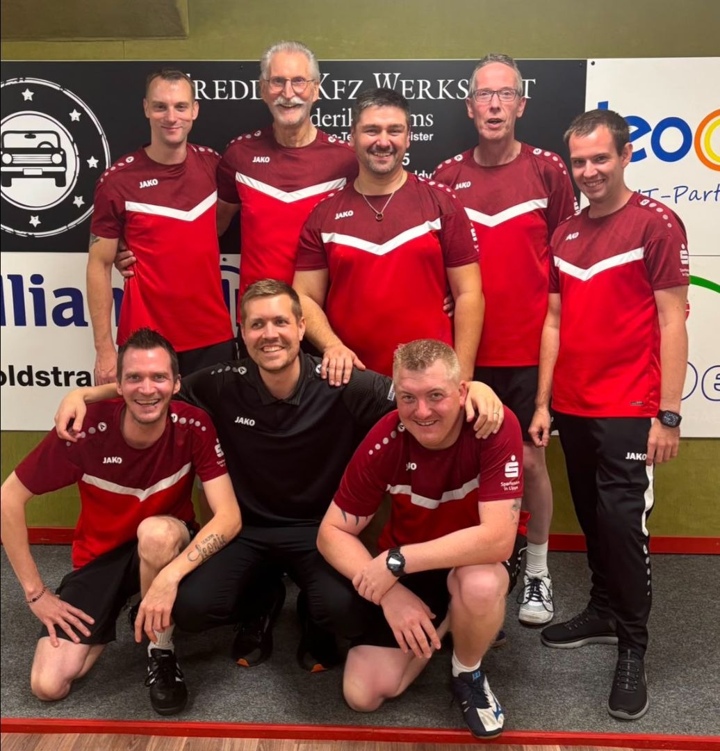 Acht lächelnde Männer in roten Sporttrikots, stehend und kniend, posieren vor einer Kegelbahn mit Sponsorenlogos