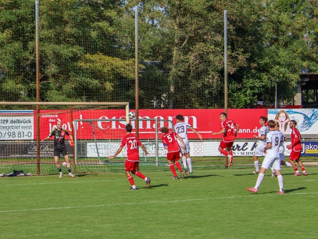 Delbrück-Spieler köpft im Fußballspiel den Ball vor dem Tor, umringt von Spielern des TuS Lipperreihe