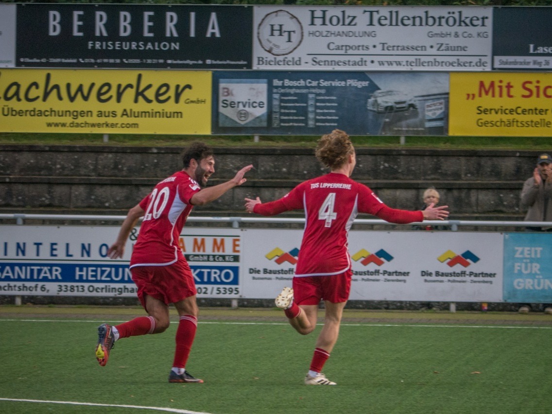Zwei Fußballspieler des TuS Lipperreihe in roten Trikots jubeln auf dem grünen Rasen