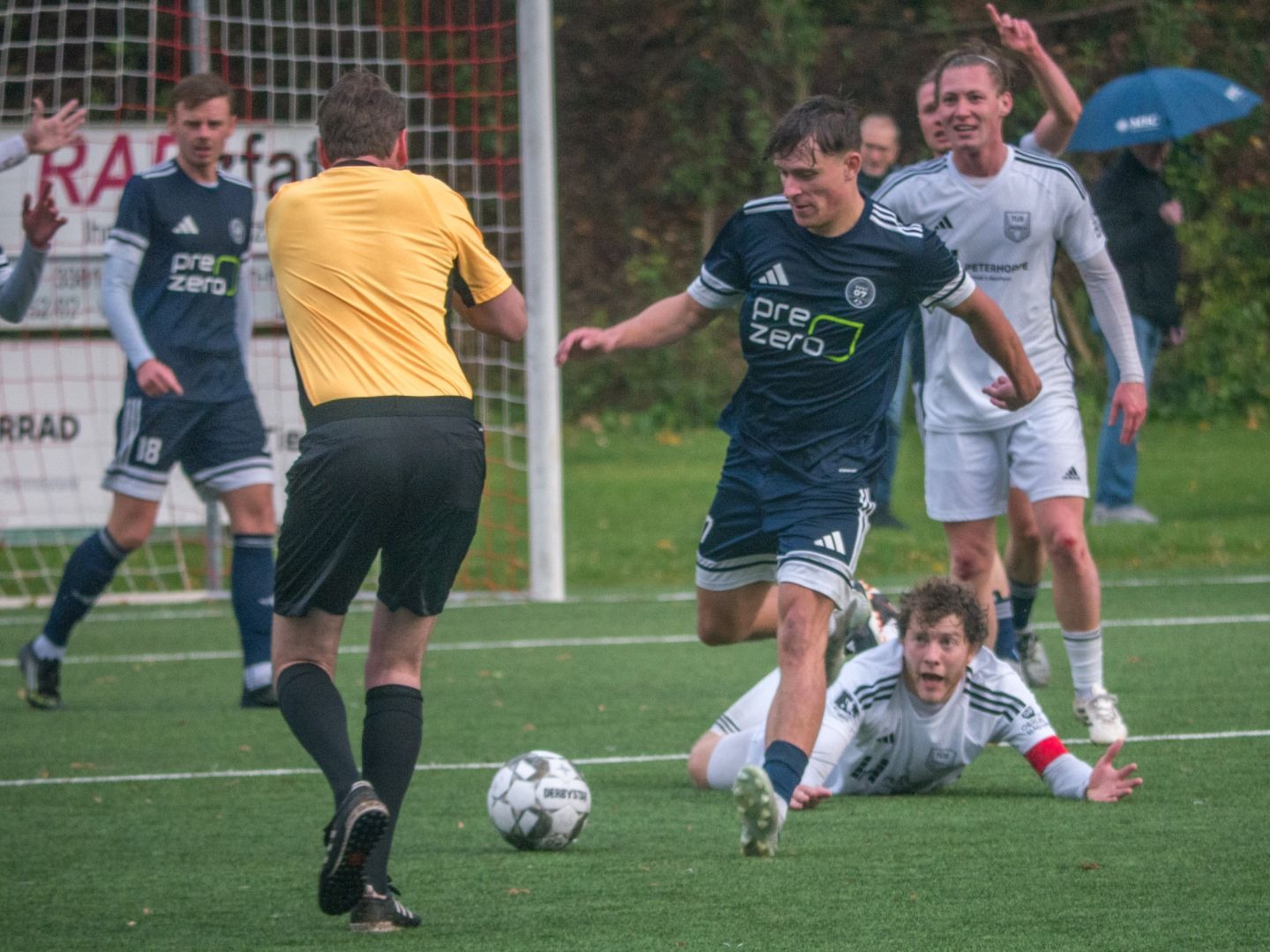 Spieler von SVKT 07 Minden mit Ball, ein TuS Lipperreihe Spieler liegt am Boden, daneben ein Schiedsrichter