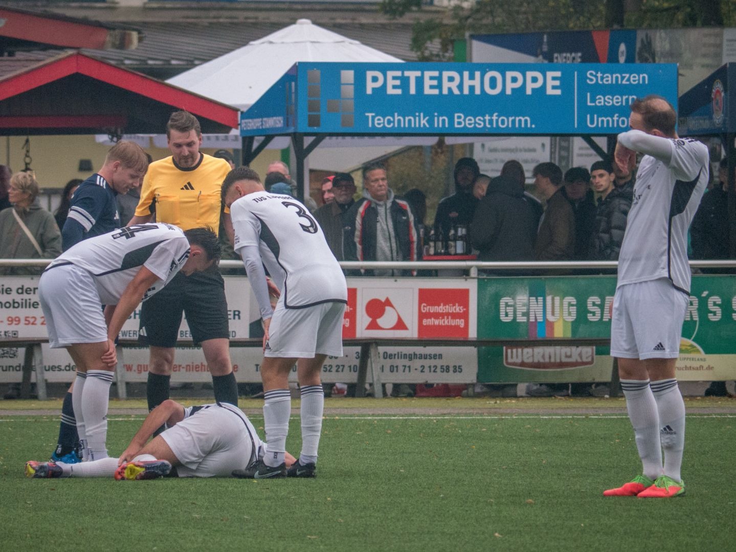 Ein Spieler von TuS Lipperreihe liegt verletzt auf dem Fußballrasen, umgeben von Schiedsrichter und Teamkameraden