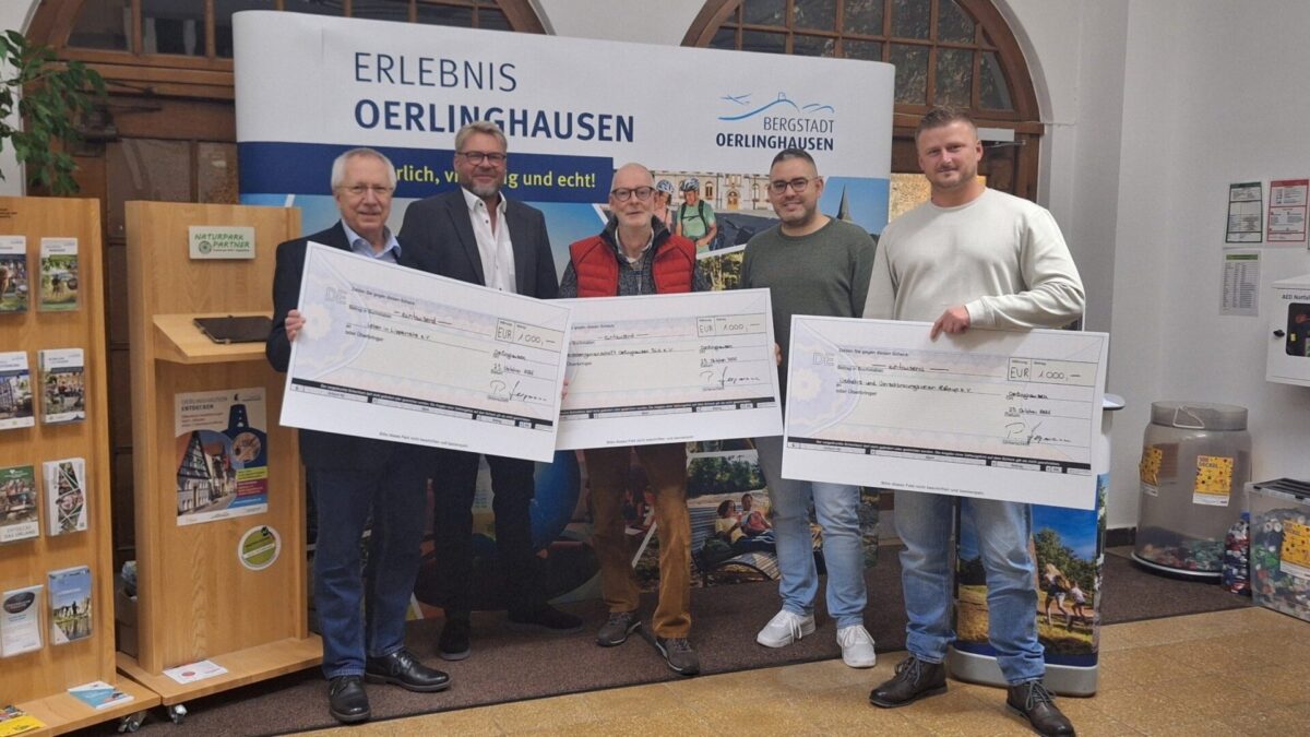 Fünf Männer präsentieren jeweils einen 1.000-Euro-Scheck für lokale Projekte in Oerlinghausen vor einem Werbebanner