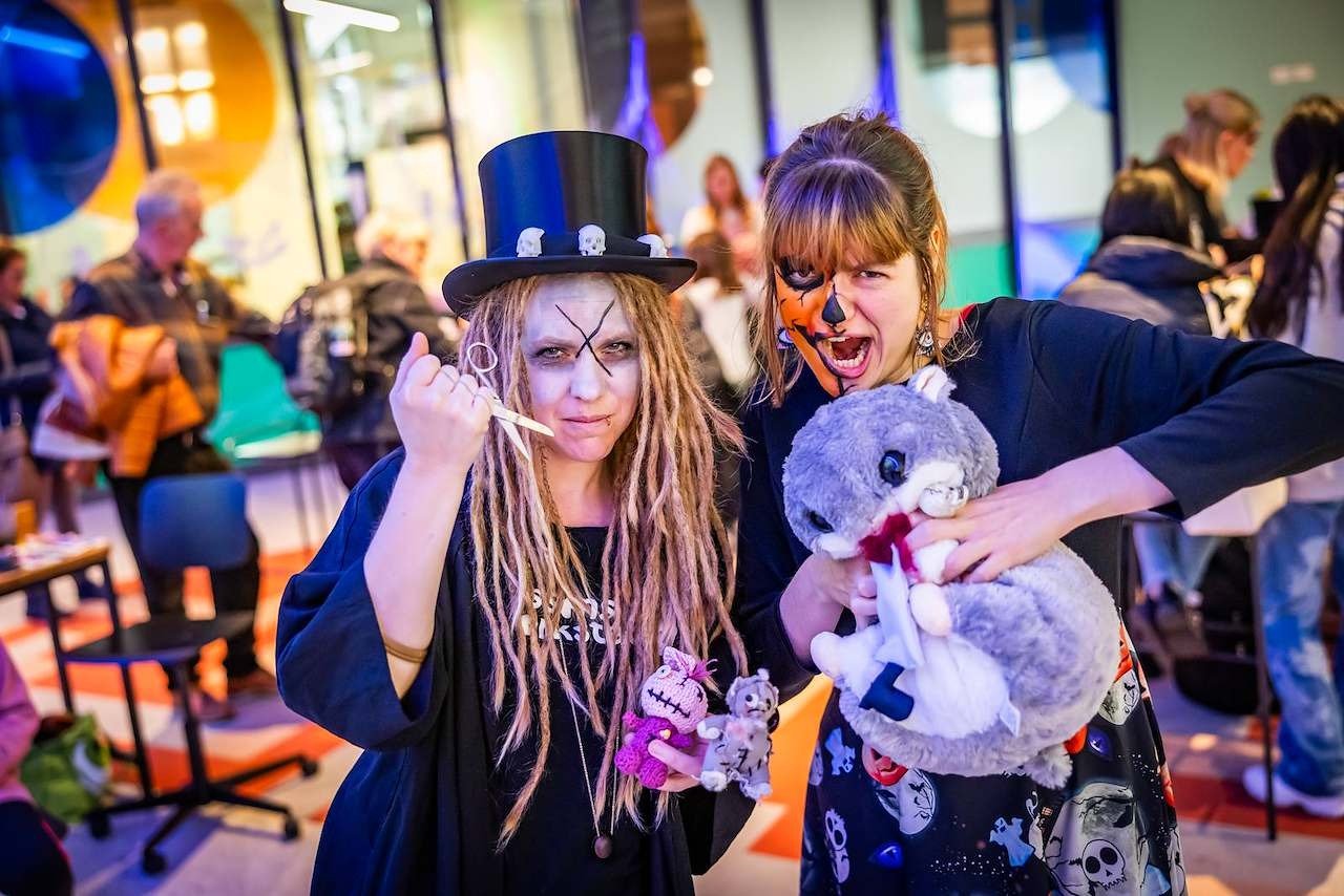 Zwei kostümierte Frauen: eine mit Zylinder, Dreadlocks und Schere; die andere mit Kürbisgesicht und Plüschtieren